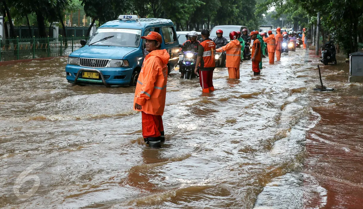 Petugas PPSU Srengseng Sawah melakukan pengaturan kendaraan yang melintas di jalan Lenteng agung, Jakarta, (12/2). Akibat Hujan deras,  jalan Lenteng Agung tepat di depan Universitas Pancasila  tergenang banjir hingga 50 cm. (Liputan6.com/Yoppy Renato)