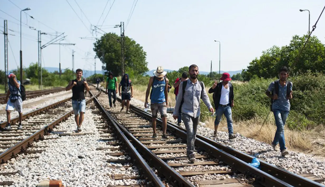Sejumlah imigran berjalan menyusuri rel kereta api saat perjalanan menuju Gevgelija, wilayah perbatasan Macedonia-Yunani, Kamis (9/7/2015). Mereka menempuh ribuan kilometer agar dapat mengejar kereta api tujuan Serbia. (AFP PHOTO/Robert ATANASOVSKI)