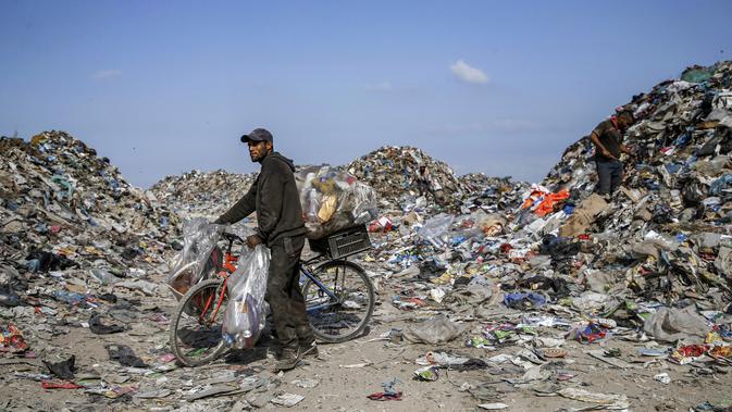 Seorang pengumpul sampah Palestina mendorong sepeda yang berisi kaleng aluminium dan sampah lainnya di tempat pembuangan sampah di Kota Gaza (29/7/2019). (AFP Photo/Mohammed)