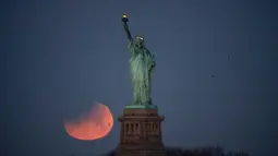 Pemandangan ketika Patung Liberty dihiasi oleh supermoon di Brooklyn, New York, Amerika Serikat, Rabu (31/1). Namun demikian, hanya sebagian gerhana yang terlihat di Pantai Timur Amerika. (AP Photo/Julio Cortez)