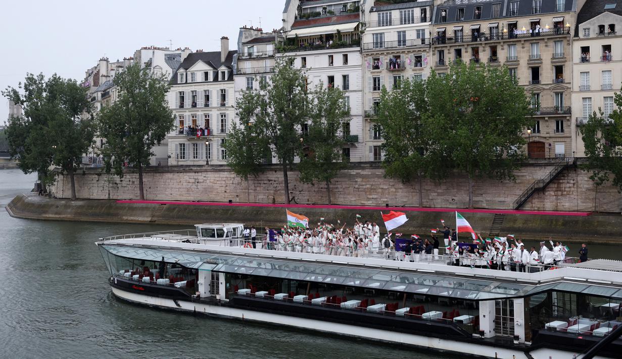 Mereka mengangkat bendera setinggi-tingginya, setinggi harapan untuk berjaya di Olimpiade 2024 Paris. Total Indonesia berkekuatan 14 atlet dan ofisial saat upacara pembukaan. (Clive Brunskill / POOL / AFP)