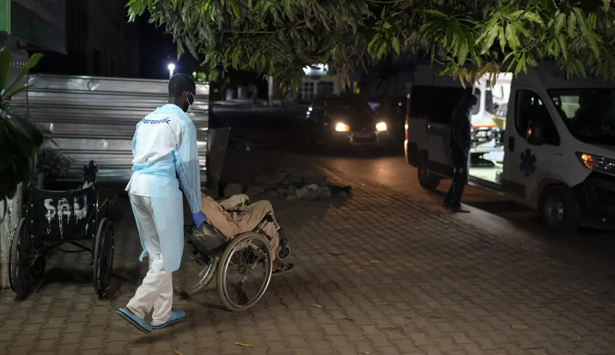 Petugas kesehatan membantu pasien COVID-19 ke ambulans untuk memindahkannya ke unit perawatan intensif di Pusat Rumah Sakit Universitas Fann di Dakar, Senegal, pada 6 Agustus 2021. Longsoran kasus datang saat Senegal menghadapi gelombang ketiga dengan kedatangan varian delta. (AP Photo/Leo Correa)