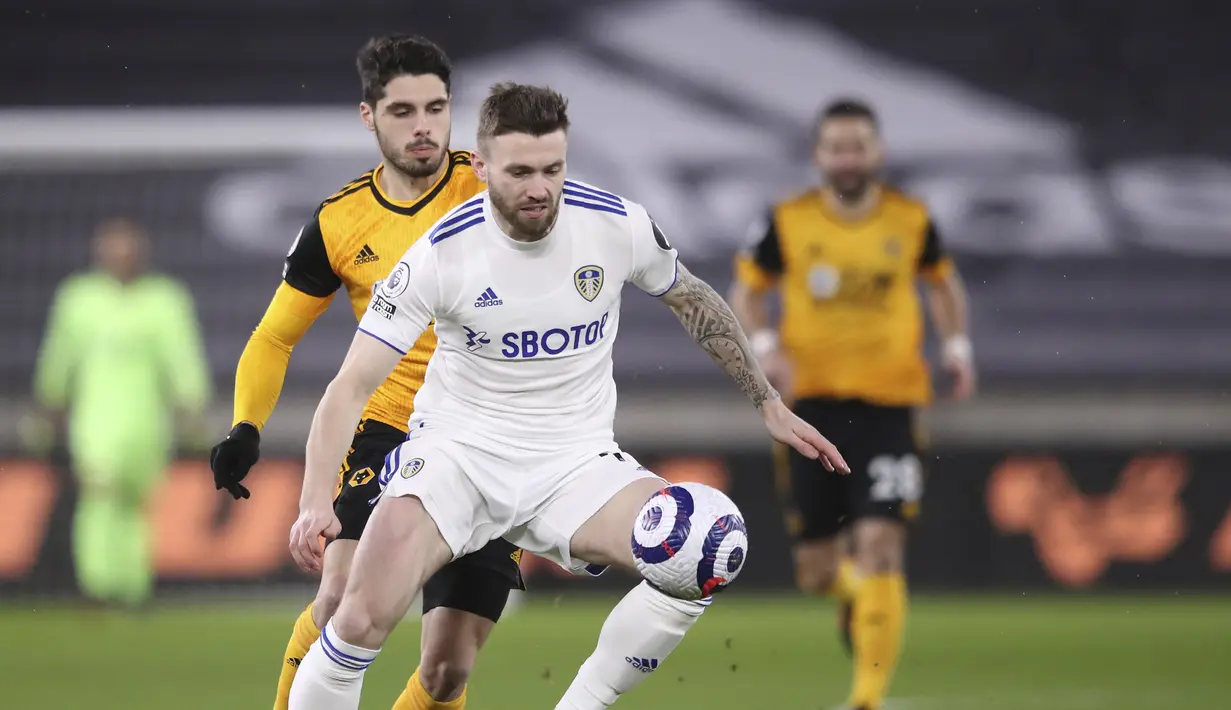 Gelandang Leeds United, Stuart Dallas (depan) menguasai bola dibayangi gelandang Wolverhampton Wanderers, Pedro Neto dalam laga Lanjutan Liga Inggris 2020/21 pekan ke-25 di Molineux Stadium, Jumat (19/2/2021). Leeds kalah 0-1 dari Wolverhampton. (AP/Alex Pantling/Pool)