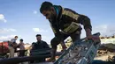 Nelayan mengangkat hasil tangkapan lautnya sebelum dikirim ke pasar di Gaza (23/5/2021). Aktivitas di kawasan Gaza perlahan kembali bergeliat usai Israel dan Hamas sepakat gencatan senjata setelah 11 hari konflik Israel dan Palestina yang memakan ratusan korban jiwa. (AP Photo/John Minchillo)