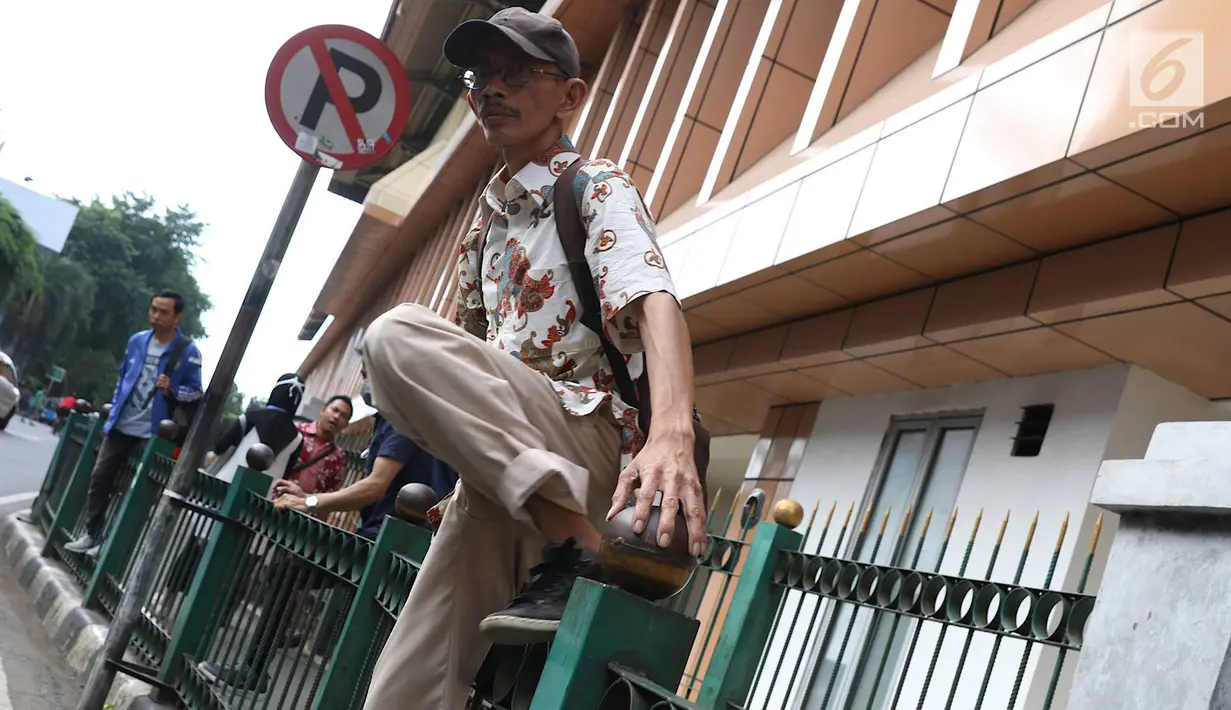 Penumpang menaiki pagar pembatas untuk keluar dari Stasiun Cikini di Jakarta, Jumat (22/3). Jauhnya akses pintu masuk dan keluar stasiun menyebabkan sebagian orang mempersingkat waktu dengan melompat pagar pembatas. (Liputan6.com/Immanuel Antonius)