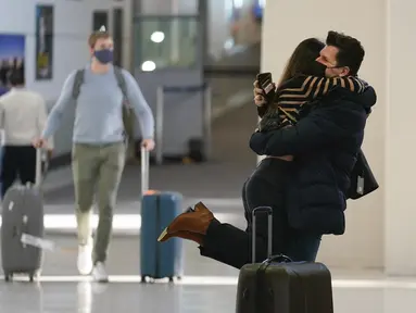 Natalia Abrahao diangkat tunangannya Mark Ogertsehnig saat mereka bertemu kembali di Bandara Internasional Newark Liberty di Newark, New Jersey, Senin (8/11/2021). AS membuka kembali perbatasannya mulai Senin untuk pengunjung asing, mengakhiri larangan masuk selama 20 bulan. (AP Photo/Seth Wenig)