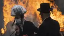Pria Yahudi Ultra-Ortodoks memakai masker saat membakar beragi sebagai persiapan akhir untuk liburan Paskah di kota Yahudi ultra-Ortodoks Bnei Brak, dekat Tel Aviv, Israel (26/3/2021).  Dalam perayaan ini umat Yahudi dilarang memakan makanan beragi seperti roti tawar. (AP Photo/Oded Balilty)