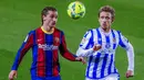 Penyerang Barcelona, Antoine Griezmann, berebut bola dengan pemain Real Sociedad, Nacho Monreal, pada laga Liga Spanyol di Stadion Camp Nou, Kamis (17/12/2020). Barcelona menang dengan skor 2-1. (AP/Joan Monfort)