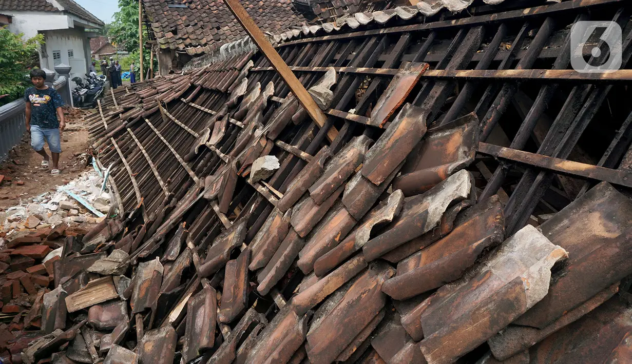 Seorang warga melintas di dekat rumah warga yang ambruk setelah diguncang gempa di Dusun Krajan, Majangtengah, Dampit, Kabupaten Malang, Minggu (11/4/2021). Sejumlah rumah yang rusak berat terpaksa dirobohkan untuk meminimalisir adanya korban jika terjadi gempa susulan (merdeka.com/Nanda F. Ibrahim)