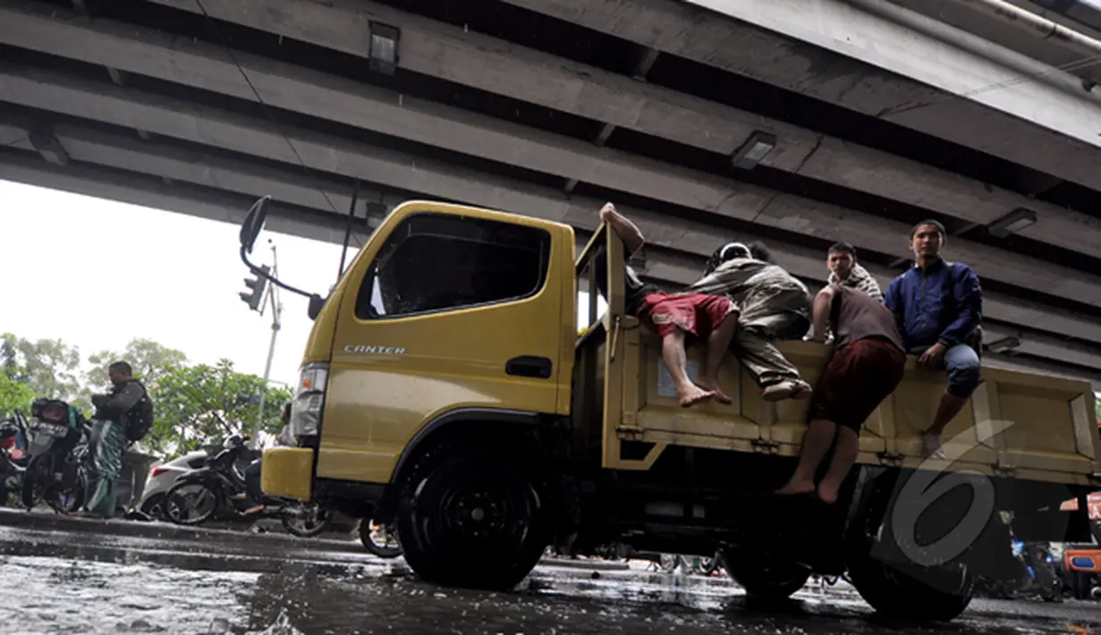 Sejumlah orang berusaha menaiki truk yang lewat untuk menumpang melawati banjir, Jakarta, Senin (6/2/2015).  Hujan yang turun sejak malam hingga kini membuat sejumlah ruas jalan di ibukota banjir. (Liputan6.com/Faizal Fanani)