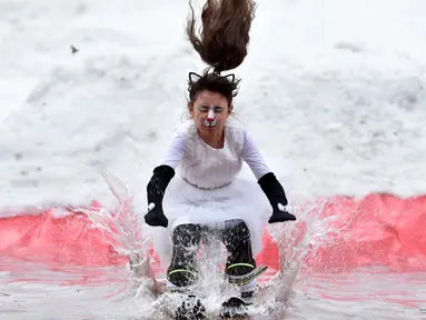 Seorang peserta dengan mengenakan kostum melompat ke dalam kolam sebagai bagian dari kompetisi komik 'Californication 9.0' di kota Logoisk, utara Minsk, Belarus, 7 April 2019. Sebanyak 8 peserta dengan kostum unik berseluncur salju untuk merayakan  akhir musim dingin. (Sergei GAPON / AFP)