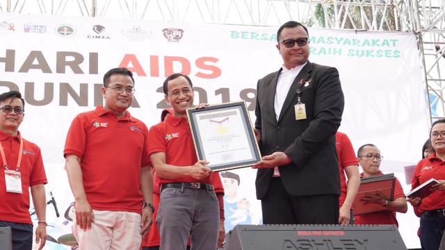 Dirjen Pencegahan dan Pengendalian Penyakit Kemenkes, Anung Sugihantono menerima piagam pemecahan rekor MURI terkait formasi pita merah AIDS. (Foto: Humas Kemenkes)