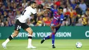 Penyerang Barcelona, Ansu Fati, berusaha melewati bek Valencia, Ezequiel Garay, pada laga La Liga di Stadion Camp Nou, Sabtu (14/9). Barcelona menang 5-2 atas Valencia. (AP/Joan Monfort)