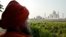Seorang pria berdiri di seberang Taj Mahal dari tepi sungai Yamuna di Agra, Jumat (4/5). India tengah dirundung kekhawatiran akan perubahan warna pada salah satu situs bersejarah dunia, Taj Mahal karena terpapar polusi. (AFP/CHANDAN KHANNA)