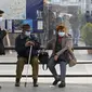 Orang-orang yang memakai masker untuk mengekang penyebaran COVID-19 duduk di halte bus di pusat Kota Lisbon, Portugal, 29 November 2021. Otoritas kesehatan Portugal mengidentifikasi 13 kasus COVID-19 varian Omicron. (AP Photo/Ana Brigida)