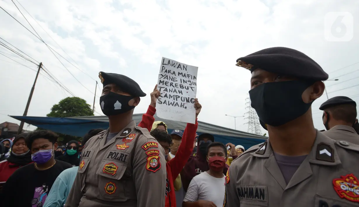 Polisi berjaga saat warga Kampung Sawah melakukan aksi dengan menutup akses jalan Cakung Cilincing, Jakarta, Rabu (18/11/2020). Aksi tutup jalan ini sebagai bentuk protes warga atas hak tanahnya yang terkena proyek pembangunan jalan tol Cakung Cilincing (Cacing)-Cibitung. (merdeka.com/Imam Buhori)