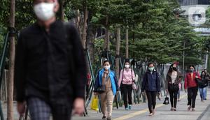 Pegawai pulang kerja berjalan di trotoar Jalan Sudirman, Jakarta, Selasa (12/5/2020). Pemerintah memberi kelonggaran bergerak bagi warga berusia di bawah 45 tahun untuk mengurangi angka pemutusan hubungan kerja (PHK) akibat pandemi virus corona COVID-19. (Liputan6.com/Johan Tallo)