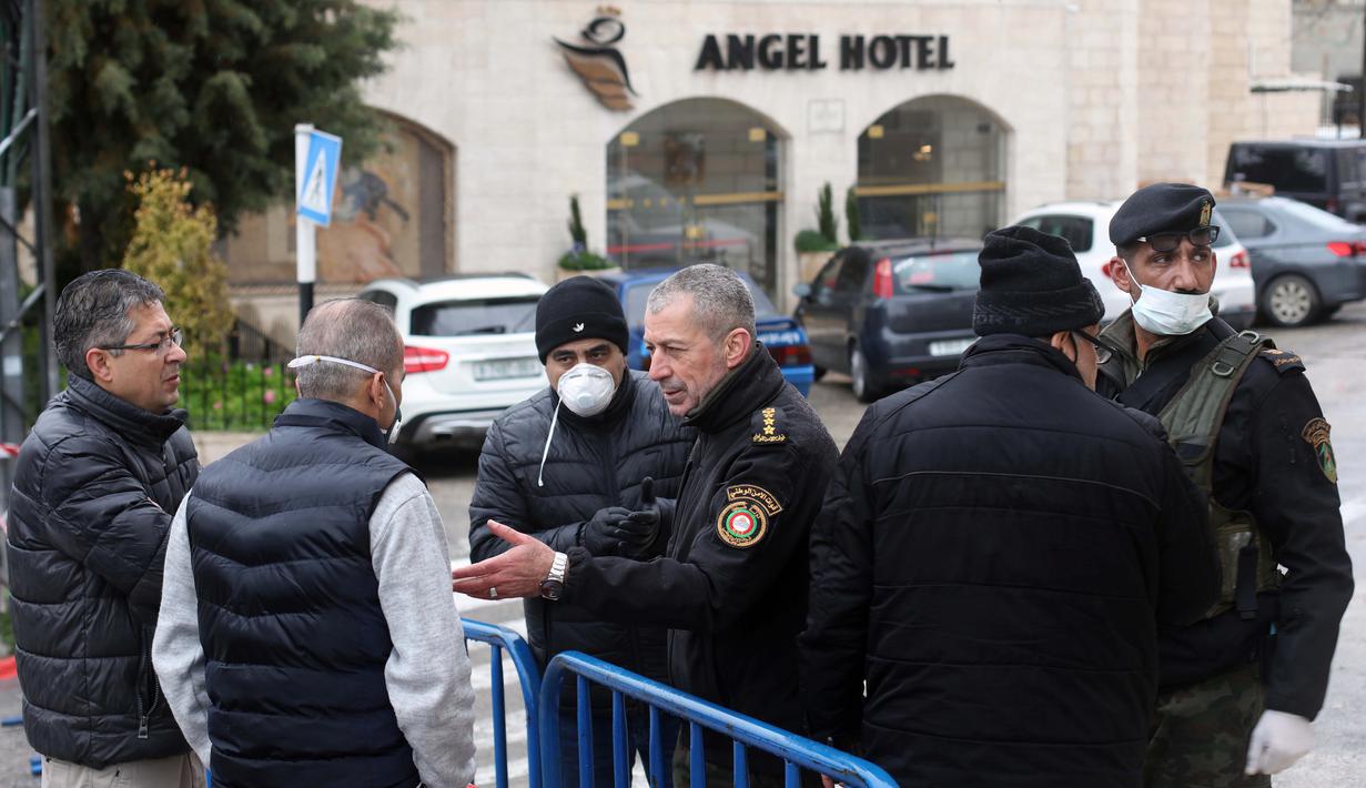 Sejumlah aparat kepolisian Palestina berjaga-jaga di luar Angel Hotel di Kota Betlehem, Tepi Barat, pada 6 Maret 2020. Keadaan darurat mulai diberlakukan pada Jumat (6/3) di Palestina di tengah kekhawatiran penyebaran coronavirus baru. (Xinhua/Stringer)