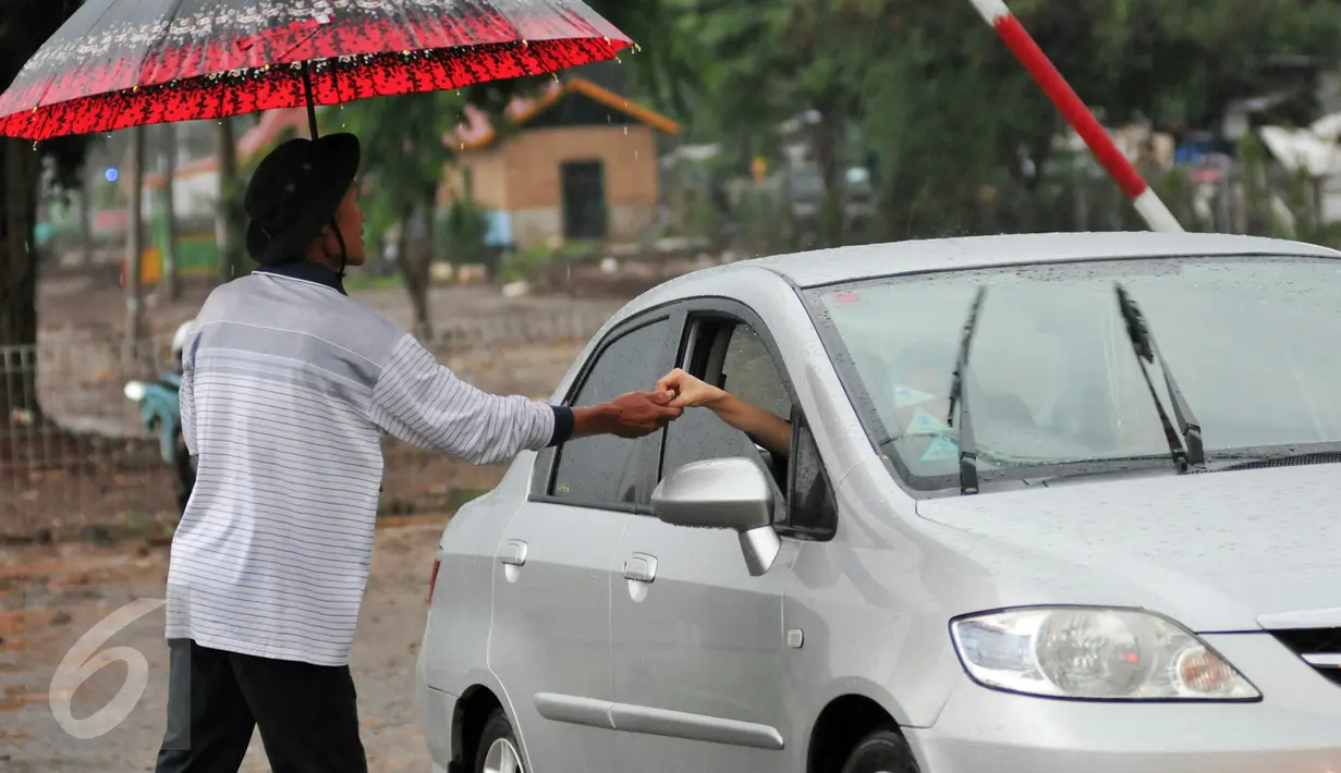 Muhamad Ali menerima uang dari pengendara yang melintas di perlintasan kereta Pondok Cina. Ia dengan tekun menjaga perlintasan kereta meski tak digaji pemerintah setempat, Depok, Minggu (13/12/2015). (Liputan6.com/Yoppy Renato)
