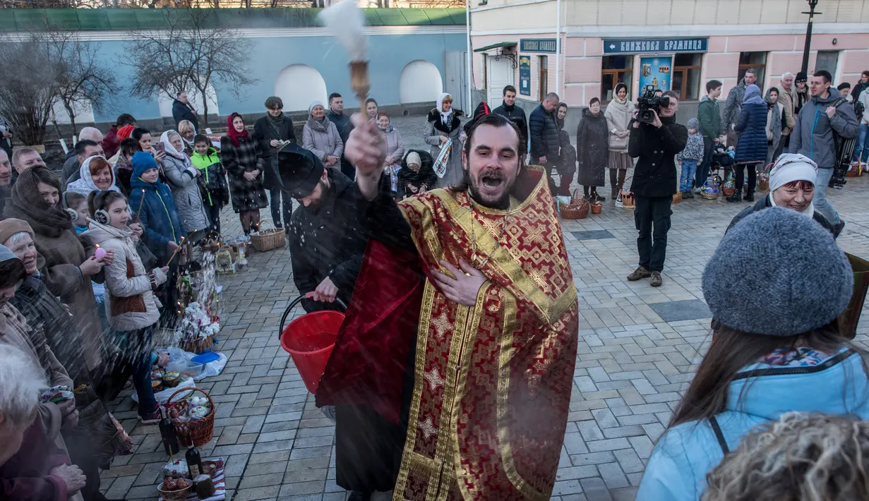Imam Ortodoks Ukraina mencipratkan air saat memberkati jemaatnya dalam perayaan Paskah di Biara Volodymyrskiy di Kiev, Ukraina (8/4). Mereka melakukan Paskah sesuai kalender Julian kuno. (AP Photo / Evgeniy Maloletka)