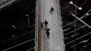 Warga berjalan di jembatan yang tertutup salju tebal di Tokyo (22/1). Badan cuaca Jepang mengeluarkan peringatan salju pertamanya di kota tersebut setelah empat tahun terakhir.  (AP Photo/Shizuo Kambayashi)