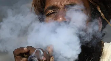 Seorang Sadhu atau orang suci Hindu menghisap ganja menggunakan 'chillum', pipa tanah liat tradisional, menjelang festival Hindu 'Maha Shivaratri', di Kathmandu (9/3/2021). Festival ini dirayakan sebagai bentuk persembahan kepada Dewa Siwa. (AFP/Prakash Mathema)