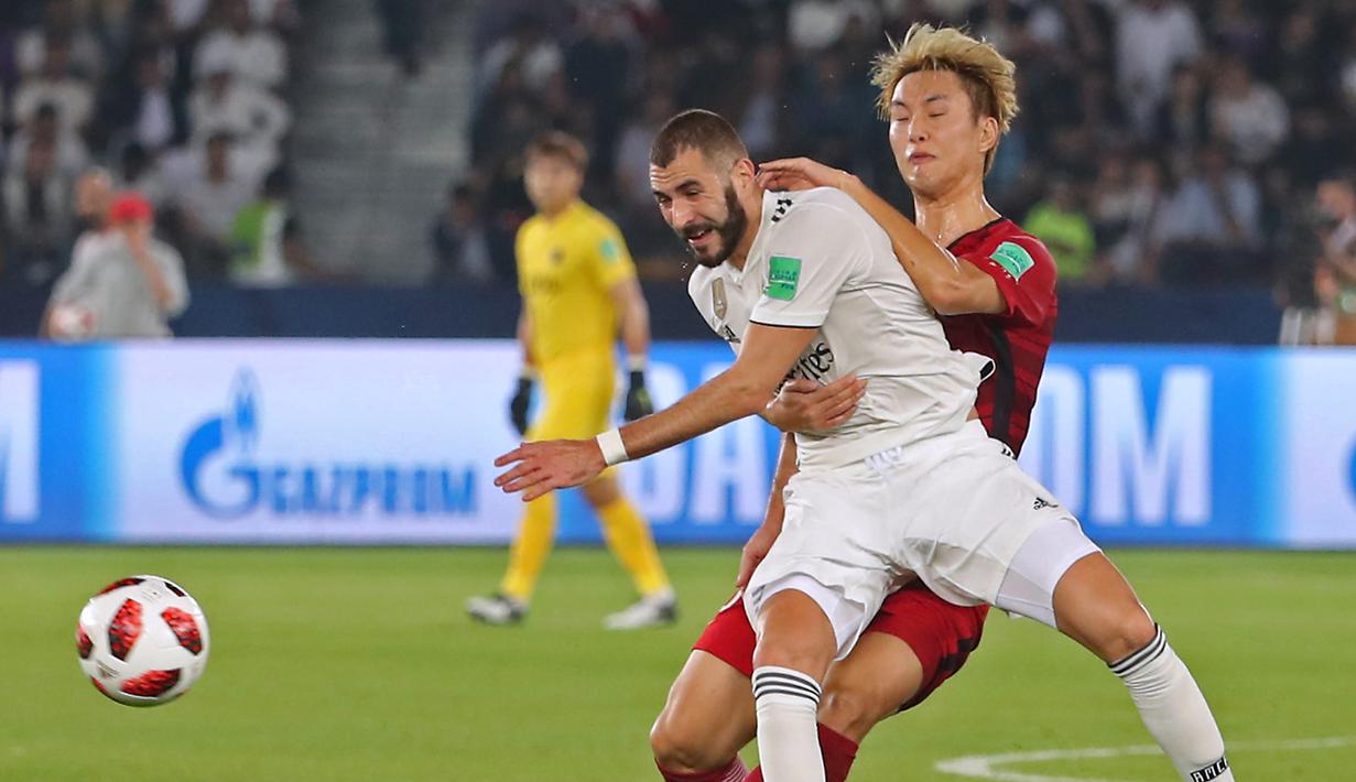 Striker Real Madrid, Karim Benzema, berusaha melewati bek Kashima Antlers, Jung Seung-Hyun, pada laga Piala Dunia Antarklub di Stadion Zayed Sports City, Abu Dhabi, Rabu (19/12). Madrid menang 3-1 atas Kashima. (AFP/Giuseppe Cacace)