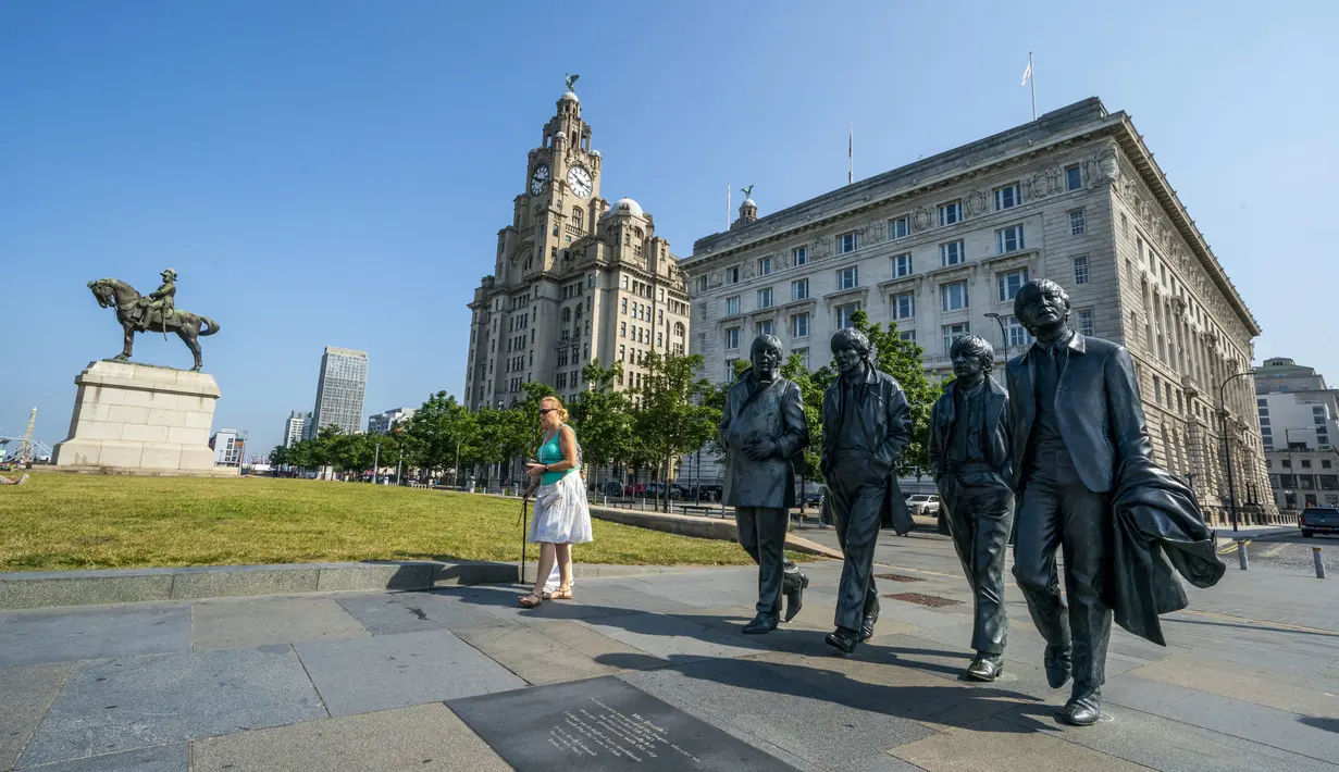 Patung The Beatles dan Royal Liver Building di tepi pantai Liverpool, Rabu (21/7/2021). Kota Liverpool Inggris telah dihapus dari daftar situs warisan dunia UNESCO karena hadirnya bangunan baru, termasuk stadion baru klub bola Everton, yang merusak daya tarik dermaga Victoria. (Peter Byrne/PA via AP