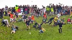 Peserta berlomba mengejar keju dalam kompetisi Cheese Rolling di Bukit Cooper, Gloucestershire, Inggris, Senin (27/5/2019). (Ben Birchall/PA via AP)
