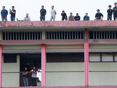 Penonton menyaksikan pertandingan antara Arema FC melawan PSM Makassar dari atap asrama Kepolisan pada laga BRI Liga 1 di Stadion PTIK, Jakarta, Sabtu (4/2/2023). PSM Makassar menang dengan skor 1-0. (Bola.com/M Iqbal Ichsan)