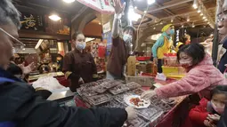 Pengunjung mencicipi jajanan kering di pasar Jalan Dihua di Taipei, Taiwan, Jumat, 20 Januari 2023. Pembeli Taiwan mulai berburu makanan lezat, jajanan kering, dan barang murah lainnya di pasar menjelang perayaan Tahun Baru Imlek yang menurut kalender lunar akan berlangsung pada 22 Januari. (AP Photo/Chiang Ying-ying)