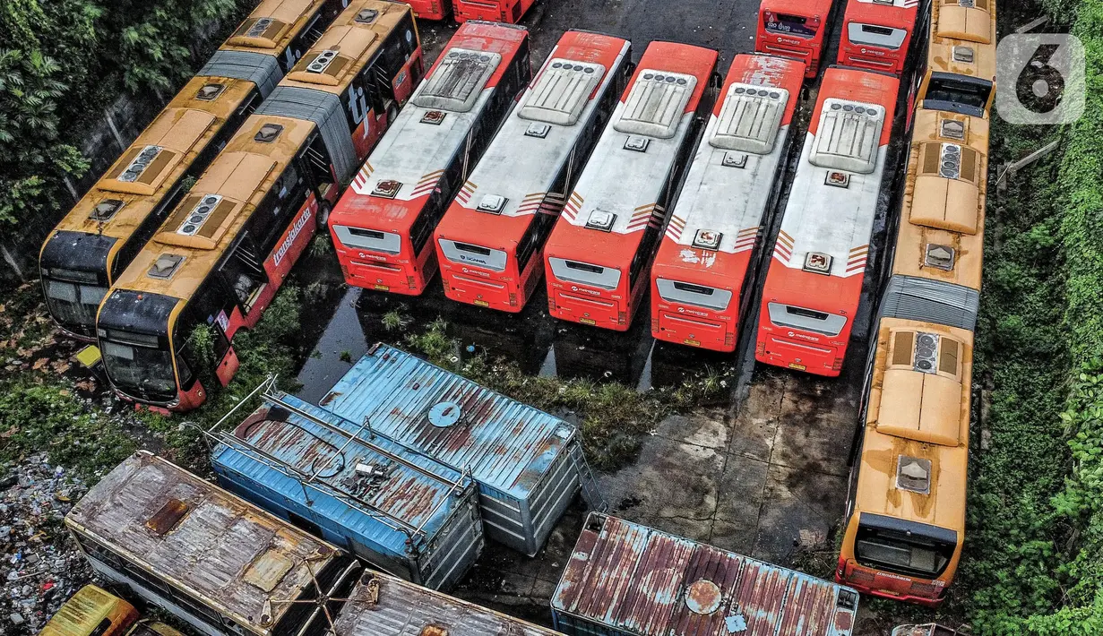 Pandangan udara puluhan bus Transjakarta saat terbengkalai di area Terminal Pinang Ranti, Jakarta Timur, Rabu (21/12/2022). Menurut petugas parkir setempat, sekitar 25 bus Transjakarta tersebut terbengkalai dan sudah tidak beroperasi sejak awal pandemi Covid-19. Beberapa bus pun terlihat berkarat dan tertutup pepohonan. (merdeka.com/Iqbal S. Nugroho)