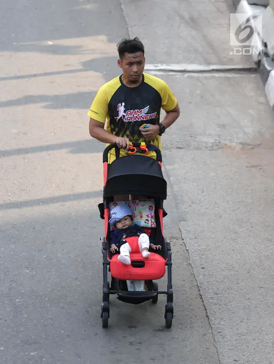 Seorang warga berolahraga sambil mendorong kereta bayi di kawasan Jalan Jenderal Sudirman hingga Jalan Thamrin, Jakarta, Minggu (17/6). Meski HBKB atau CFD ditiadakan, sebagian warga tetap berolahraga di kawasan ini. (Liputan6.com/Arya Manggala)