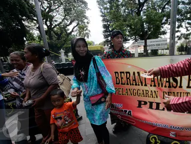 Petugas Panwas Kota Yogyakarta membagikan stiker saat sosialisasi pilkada bebas uang politik di kawasan Titik Nol Kilometer, Senin (1/8). Kegiatan tersebut untuk mensosialisasikan pelaksanaan pilkada serentak 2017 mendatang. (Liputan6.com/Boy Harjanto)