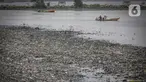 Nelayan melintas di dekat tumpukan sampah laut di muara Kanal Timur di Marunda Kepu, Cilincing, Jakarta, Kamis (8/6/2023). (Liputan6.com/Faizal Fanani)