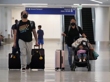 Pelancong membawa barang bawaan mereka di area pengambilan bagasi di Bandara Internasional Los Angeles, Senin (25/4/2022). Seminggu sebelumnya, seorang hakim federal di Florida menolak persyaratan untuk memakai masker di bandara dan selama penerbangan. Aturan itu, yang dirancang untuk membatasi penyebaran COVID-19, akan berakhir pada 3 Mei. (AP Photo/Marcio Jose Sanchez)