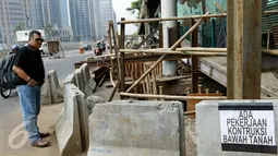 Warga berdiri di dekat pembongkaran struktur baja JPO sisi barat Polda Metro Jaya, di Jalan Jenderal Sudirman, Jakarta, Senin (23/11). Pembongkaran dilakukan karena pekerjaan konstruksi bawah tanah untuk perbaikan saluran air. (Liputan6.com/Yoppy Renato)