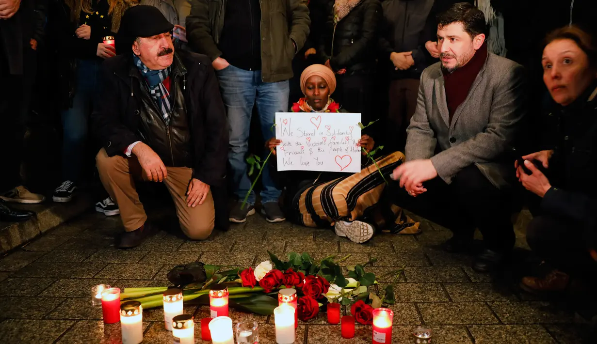 Warga menyalakan lilin saat berkabung untuk para korban penembakan brutal di Hanau di Gerbang Brandenburg Berlin, Jerman, Kamis (20/2/2020). Tersangka penembakan ditemukan tewas bersama ibunya dalam sebuah apartemen. (AP Photo/Markus Schreiber)