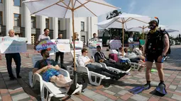 Sejumlah aktivis melakukan aksi di depan gedung parlemen Kiev, Ukraina, (12/7). Mereka membawa tulisan dan sejumlah atribut layaknya sedang di pantai.(REUTERS / Valentyn Ogirenko)