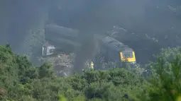 Personel layanan darurat terlihat di lokasi kecelakaan kereta api dekat Stonehaven di timur laut Skotlandia (12/8/2020). Kecelakaan tersebut telah menewaskan tiga orang dan belasan luka-luka setelah kereta penumpang tergelincir. (AFP/MICHAL WACHUCIK)