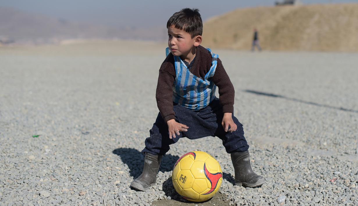 Anak laki-laki Afganistan, Murtaza Ahmadi, sedang bermain bola di Kabul, Afganistan, (1/2/2016). Lionel Messi berharap bisa bertemu dengannya setelah melihat foto Murtaza Ahmadi memakai jersey Messi dari plastik di internet. (AFP/Shah Marai)