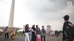 Sejumlah pengunjung berswafoto saat mengunjungi Monumen Nasional (Monas), Jakarta, Sabtu (22/12). Libur sekolah yang berbarengan dengan libur Natal dan Tahun Baru dimanfaatkan masyarakat untuk pergi berwisata ke Monas. (Liputan6.com/Faizal Fanani)