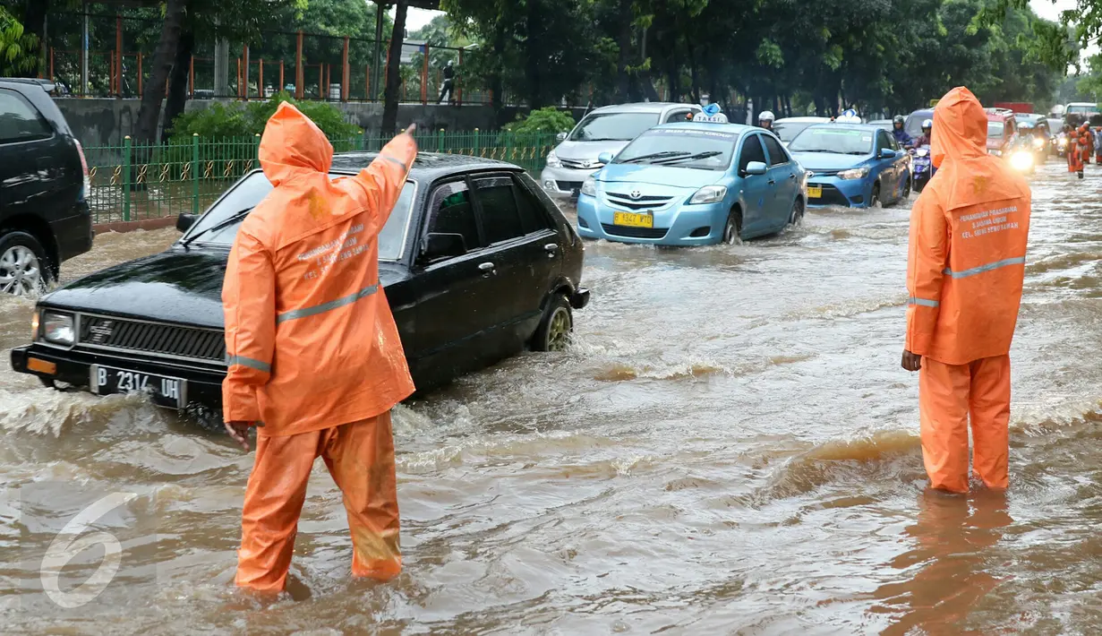 Petugas PPSU Srengseng Sawah melakukan pengaturan kendaraan yang melintas di jalan Lenteng agung, Jakarta, (12/2). Akibat Hujan deras,  jalan Lenteng Agung tepat di depan Universitas Pancasila  tergenang banjir hingga 50 cm. (Liputan6.com/Yoppy Renato)
