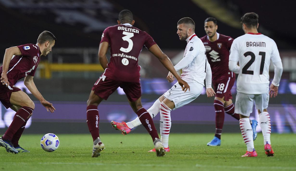 Striker AC Milan, Ante Rebic (tengah) melepaskan umpan di antara dua pemain Torino dalam laga lanjutan Liga Italia 2020/2021 pekan ke-36 di Olympic Stadium, Turin, Rabu (12/5/2021). AC Milan menang 7-0 atas Torino. (LaPresse via AP/Spada)