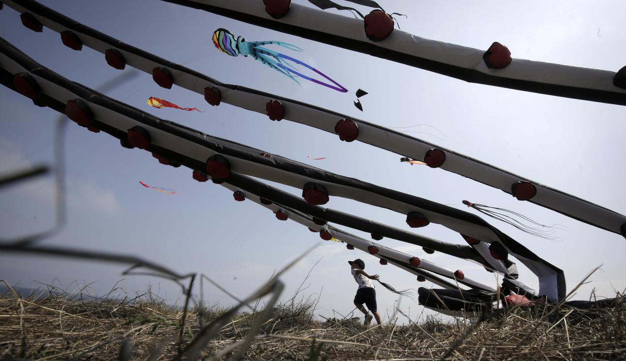Seorang anak laki-laki mengambil bagian dalam Varvara Kite Fest di Desa Varvara, pesisir Laut Hitam, Bulgaria, Jumat (27/8/2021). Penyelenggara Varvara Kite Fest Andrey Kulev mengatakan bahwa menerbangkan layang-layang seperti melepaskan semua masalah Anda di langit. (AP Photo/Valentina Petrova)