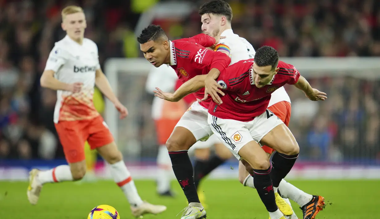<p>Pemain Manchester United Diogo Dalot dan Casemiro berebut bola dengan pemain West Ham Declan Rice selama pertandingan lanjutan Liga Inggris di stadion Old Trafford di Manchester, Inggris, Minggu, 30 Oktober 2022. Manchester United menang atas West Ham 1-0. (AP Photo/Jon Super)</p>