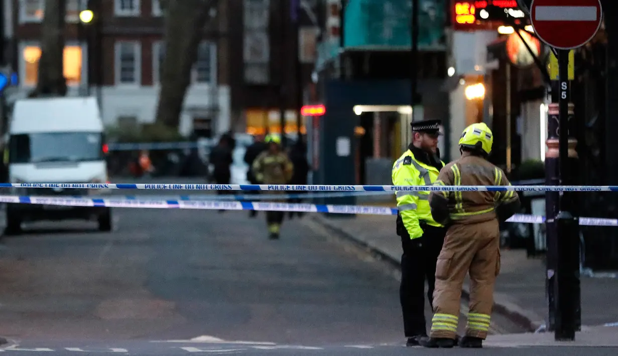 Polisi berbincang dengan petugas pemadam kebakaran saat penemuan bom Perang Dunia II di kawasan Soho, London, Inggris, Senin (3/2/2020). Polisi mengevakuasi warga yang berada di kafe, restoran, pub, dan kantor radius beberapa blok dari lokasi penemuan bom. (AP Photo/Frank Augstein)