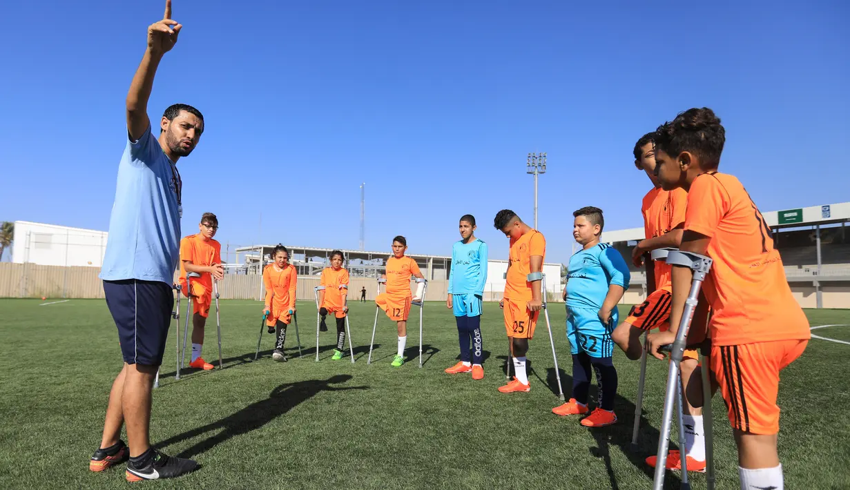 Anak-anak Palestina yang diamputasi mendengarkan pelatih dalam sesi pelatihan sepak bola, yang diatur oleh Komite Palang Merah Internasional (ICRC) setelah pembatasan penyakit coronavirus (COVID-19) mereda, di Deir al-Balah di Jalur Gaza tengah (14/7/2020). (AFP/Mahmud Hams)