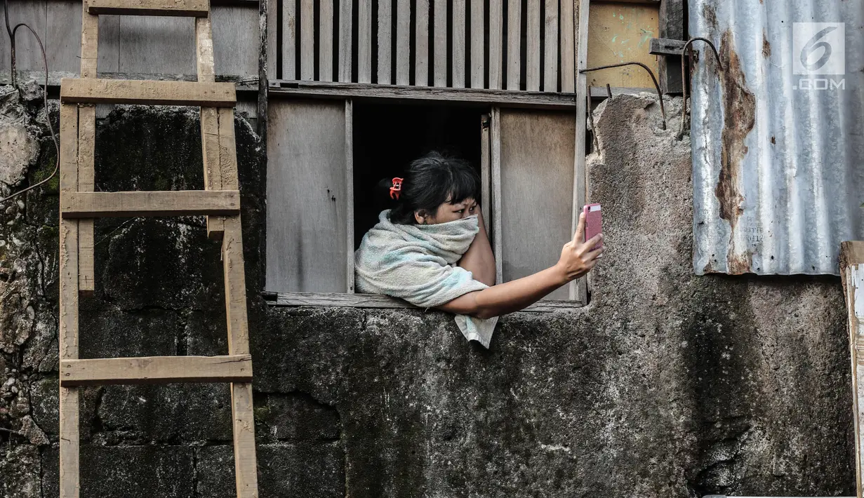 Seorang warga mengabadikan suasana penertiban bangunan dikawasan bantaran Kali Ciliwung, Kelurahan Bukit Duri, Tebet, Jakarta, Selasa (11/7). Semuanya terpusat di RT 001, 002, 003, dan 004 RW 12 Kelurahan Bukit Duri. (Liputan6.com/Faizal Fanani)