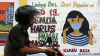Warga melintas di depan mural yang berisi pesan 3M di Jakarta, Rabu (11/11/2020). Mural tersebut dibuat untuk mengingatkan masyarakat agar menerapkan protokol kesehatan saat beraktivitas sehari-hari. (Liputan6.com/Herman Zakharia)